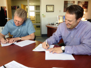 Gary Madsen and Michael Dixon signs licensing agreement at UNeMed.