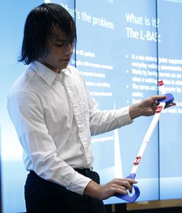 Millard South junior Harrison Pruitt demonstrates the winning design of the 2016 3D Invent-a-Thon to a panel of judges and about 28 onlookers Friday evening at UNMC's Sorrell Center.