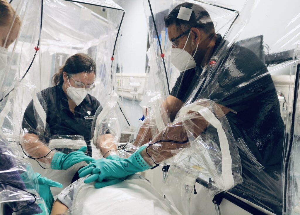 Clinical staff at UNMC/Nebraska Medicine perform life-saving procedures during a medical simulation using an early prototype of the Carecubes isolation unit. 