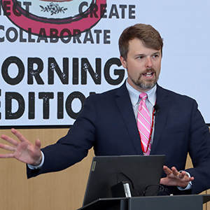 UNeMed Business Development Manager and Morning Edition organizer Tyler Scherr, PhD, addresses the gathering during brief welcoming remarks at the April 30, 2026, installment of Idea Pub: Morning Edition in the Forge Event Hall at Catalyst Omaha in the Edge District.