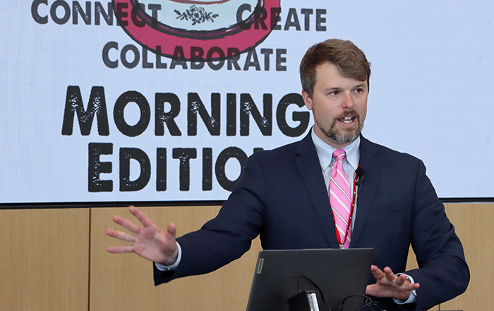 UNeMed Business Development Manager and Morning Edition organizer Tyler Scherr, PhD, addresses the gathering during brief welcoming remarks at the April 30, 2026, installment of Idea Pub: Morning Edition in the Forge Event Hall at Catalyst Omaha in the Edge District.